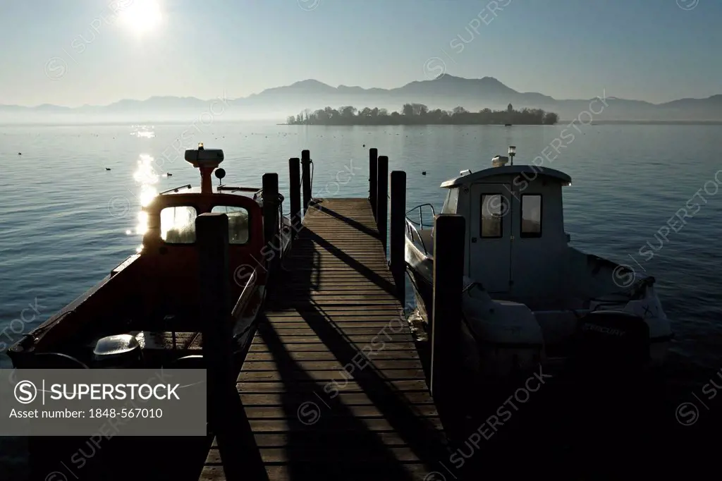 Small boats moored at the Gstadt harbour with Fraueninsel island and alpine landscape at back, lake Chiemsee, Chiemgau, Upper Bavaria, Germany, Europe