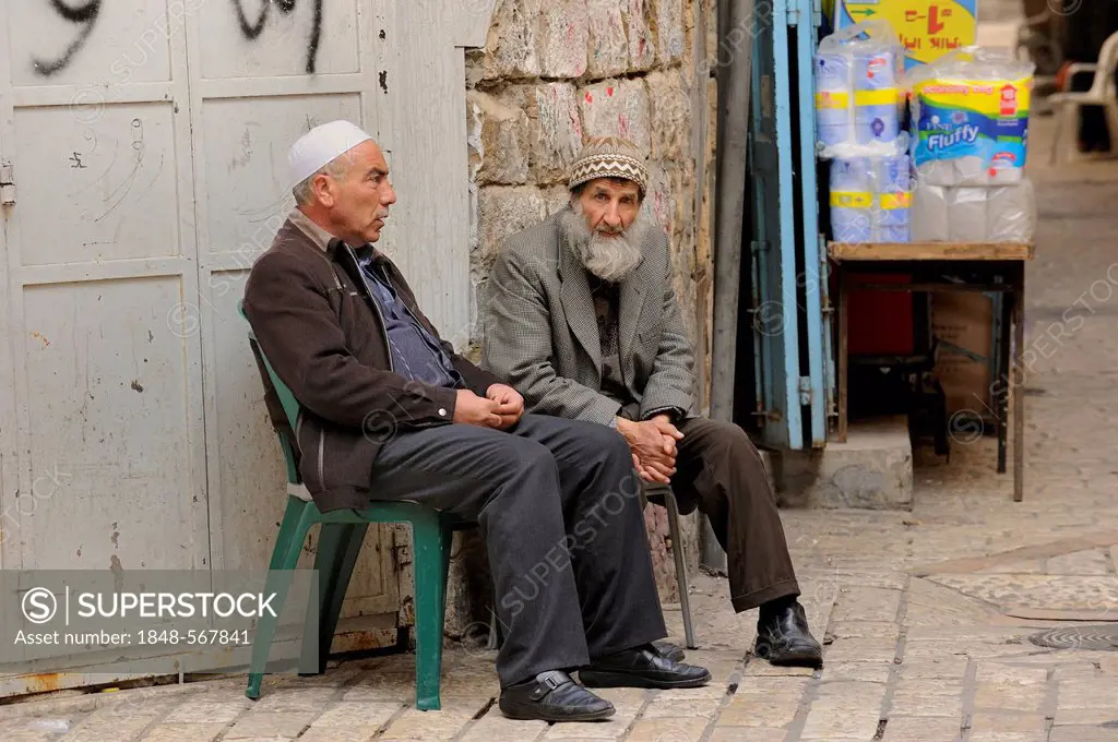 Palestinian men having a conversation at the corner of a street bazaar in a alley off Via Dolorosa, Arab Quarter, Old City, Jerusalem, Israel, Middle ...