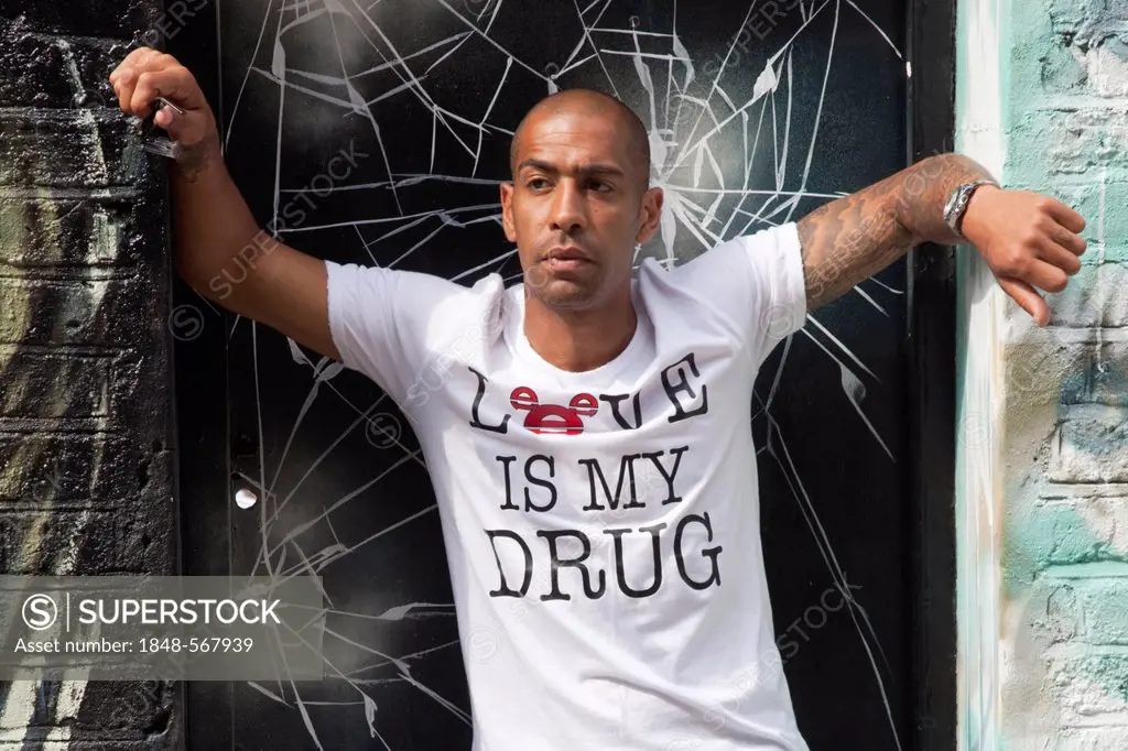 Mixed-race British man with tattoos und T-shirt with message Love is my drug, portrait, East End, London, England, United Kingdom, Europe
