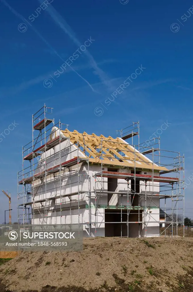 House construction site, building shell surrounded with scaffolding, with a crane in the distance, Erftkreis district, North Rhine-Westphalia, Germany...