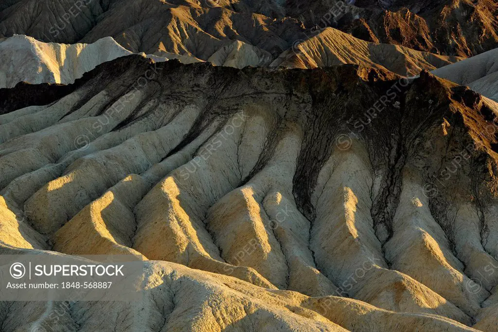 View from Zabriskie Point to eroded rocks discoloured by minerals, evening light, Death Valley National Park, Mojave Desert, California, United States...