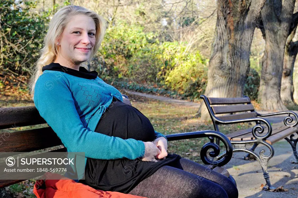 Pregnant woman, 30 years, sitting on a park bench, Dortmund, North Rhine-Westphalia, Germany, Europe