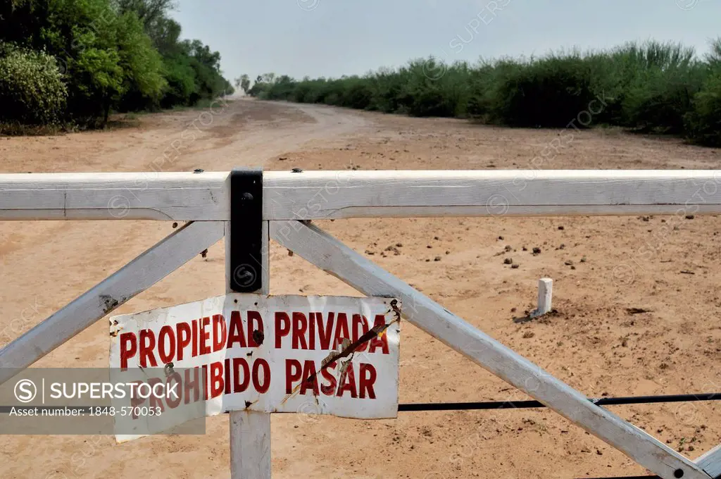 Sign on a gate Propiedad privada, Prohibido pasar, private property, access prohibited, marking the grounds of a major landowner in the Gran Chaco reg...