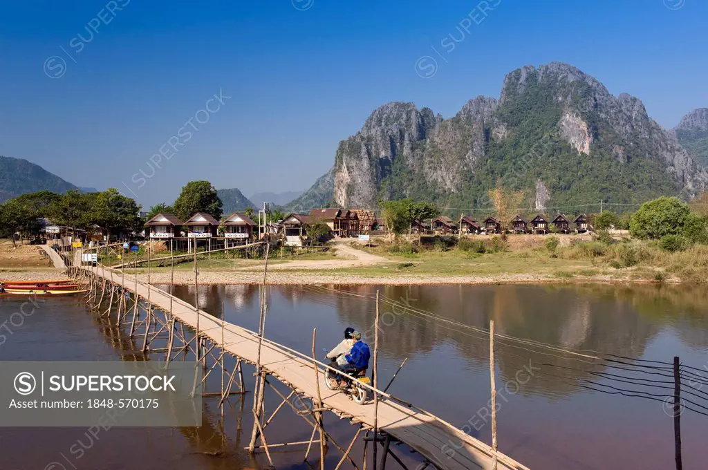 Bamboo bridge with moped rider over the Nam Song River, karst mountains, Vang Vieng, Vientiane, Laos, Indochina, Asia