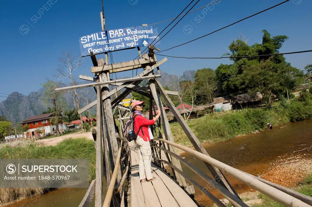 Woman walking across a wooden bridge over the Nam Song River, Vang Vieng, Vientiane, Laos, Indochina, Asia