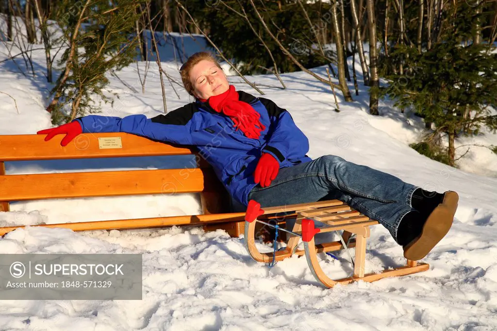 Woman, 35 years, sitting on a bench taking in the winter sun, on Mt Kickelhahn near Ilmenau, Thuringia, Germany, Europe