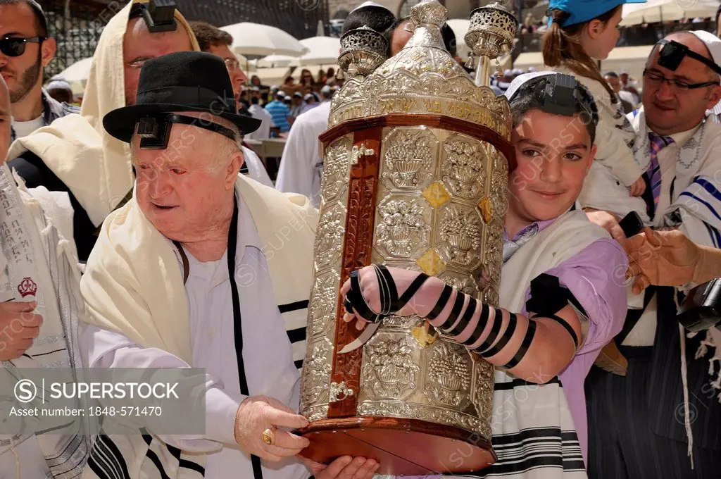 Bar Mitzvah celebration at the Western or Wailing Wall in the direction of the Jewish Quarter, boy is carrying the Torah scroll with the help of his f...