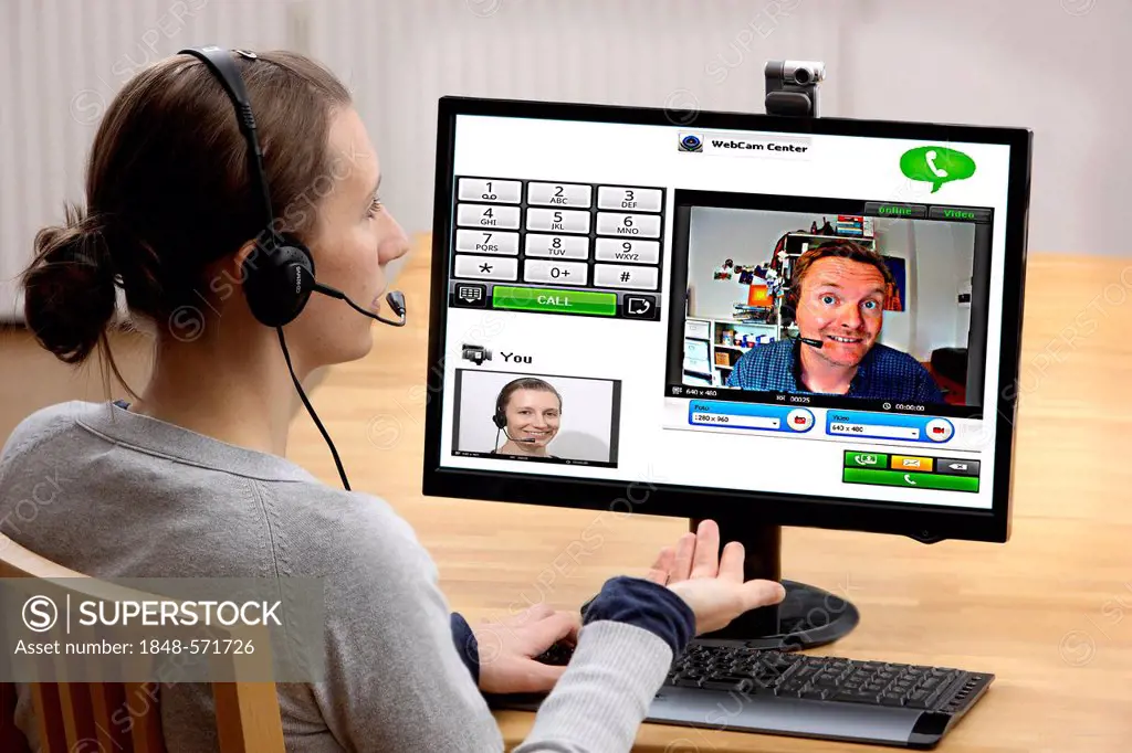 Young woman sitting at the computer and making a phone call over the Internet, via webcam, with the live images of both participants being transferred