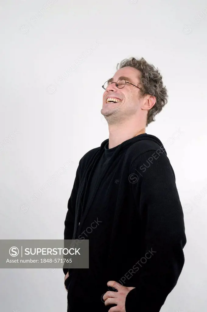 Young man with glasses laughing heartily, hands on hips