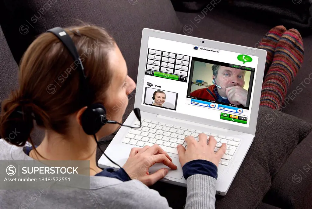 Young woman sitting with a laptop and making a phone call over the Internet, via webcam, with the live images of both participants being transferred