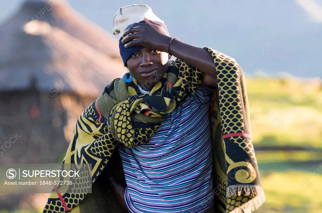 Young Basotho man wearing a traditional costume, a hut at the back, Drakensberg, Kingdom of Lesotho, southern Africa