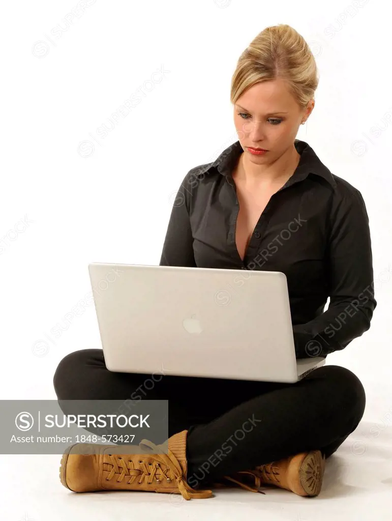 Young woman working on a laptop computer, sitting cross-legged