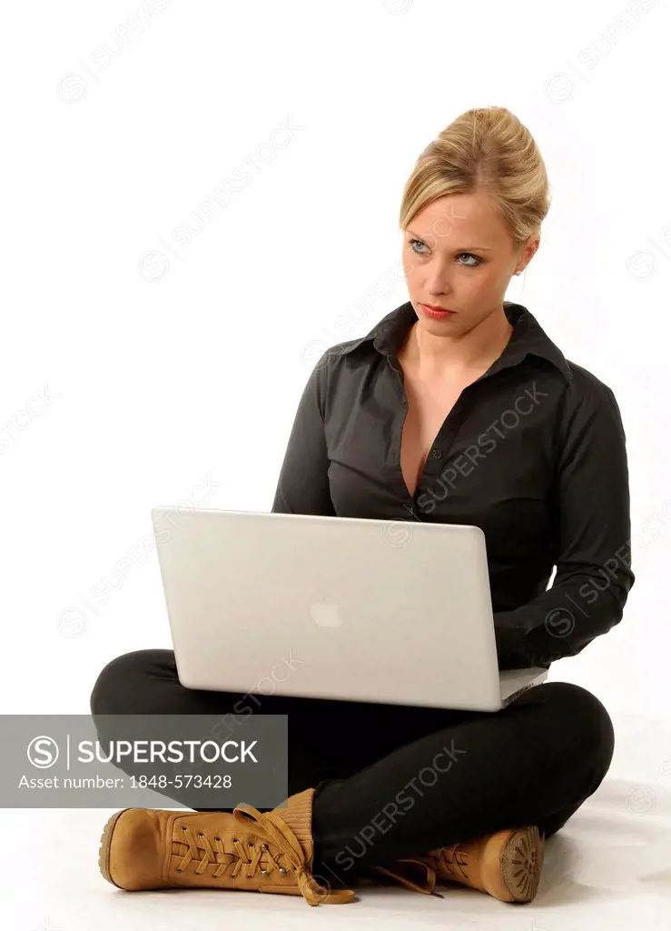 Young woman working on a laptop computer, sitting cross-legged