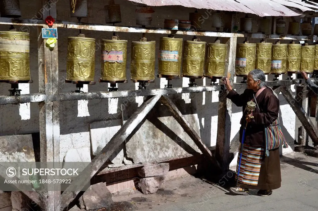 Elderly Tibetan woman in traditional costume surrounding a small temple, Meru Ningba, prayer wheels, Bakhor, near the Jokhang temple, Lhasa, Tibet, Ch...
