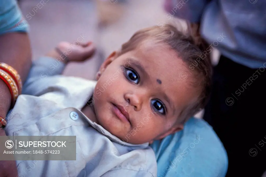Infant with kohl rimmed eyes and a Bindi on its forehead, camel and cattle market of Nagaur, Rajasthan, India, Asia