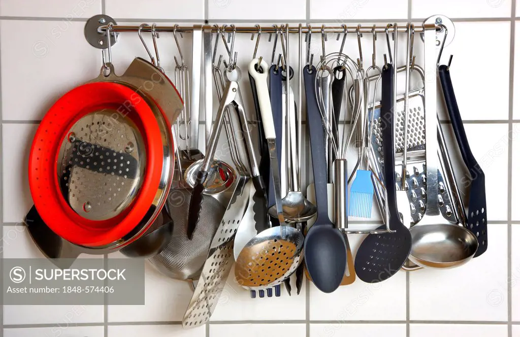 Various kitchen tools and utensils, hanging on a wall in a kitchen