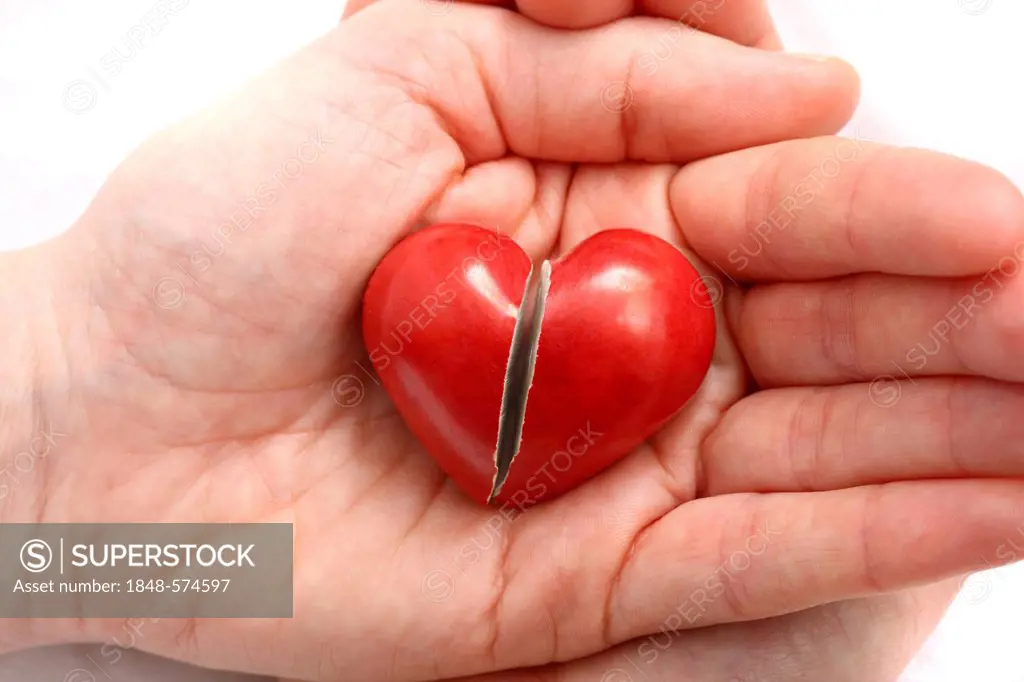 Hand holding a broken heart, symbolic image for heart disease, heart attack, a diseased heart, cardiology or heartache