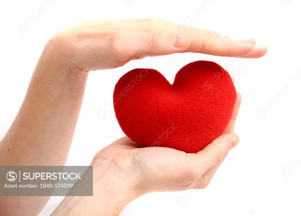 Hand being held protectively above a red heart, symbolic image for heart disease, heart attack, a diseased heart, cardiology