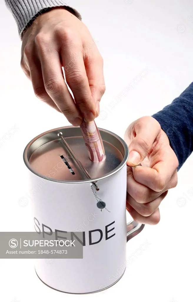 Hands with a donation box labeled Spende, German for donation, with slots for coins and bills, with a security seal to protect against unlawful openin...