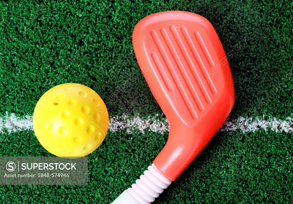 Toy plastic golf equipment, golf club and a golf ball on artificial turf