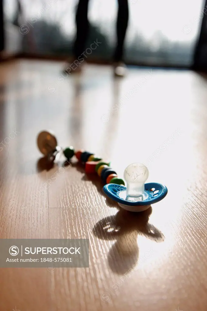 Pacifier lying on the floor, symbolic image for child abuse, violence against children