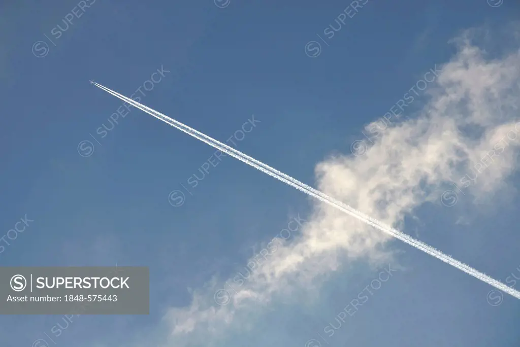 Condensation trail crossing a cloud in the sky, Germany, Europe