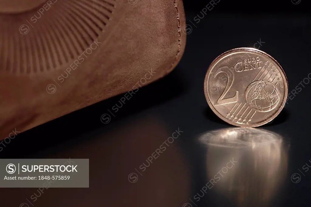 2-cent euro coin in front of a brown leather wallet or purse