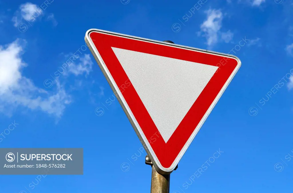 Traffic sign, give way, against a blue sky with clouds