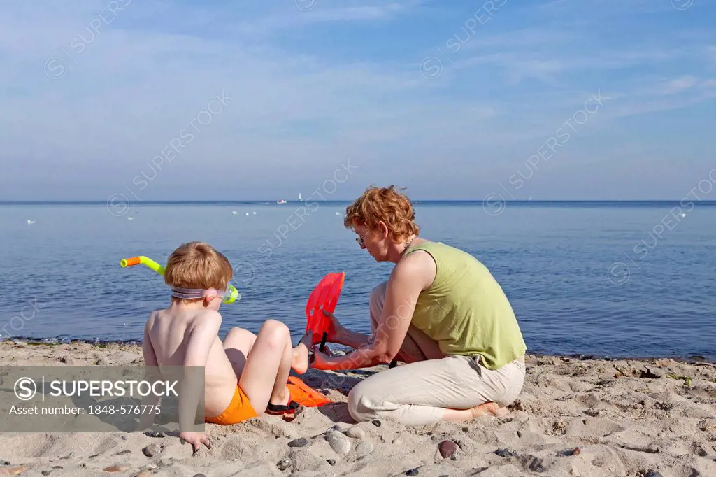 Mother helping her son put on his flippers, beach of Kuehlungsborn, Mecklenburg-Western Pomerania, Germany, Europe
