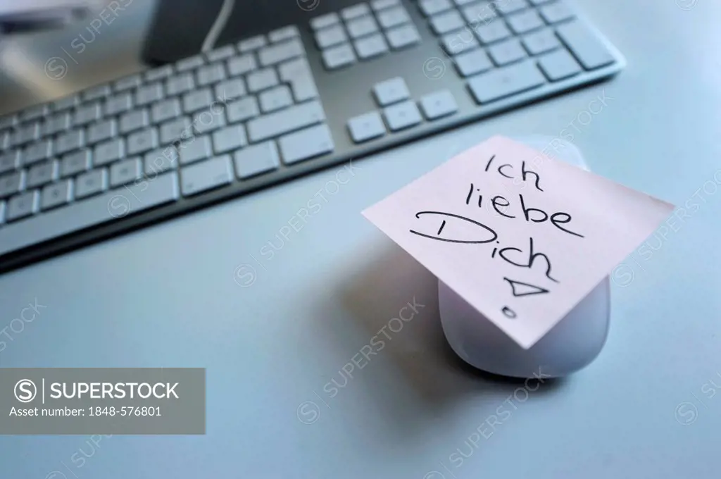 Sticky note with the words Ich liebe Dich, German for I love you, next to computer keyboard, symbolic image for love at the workplace