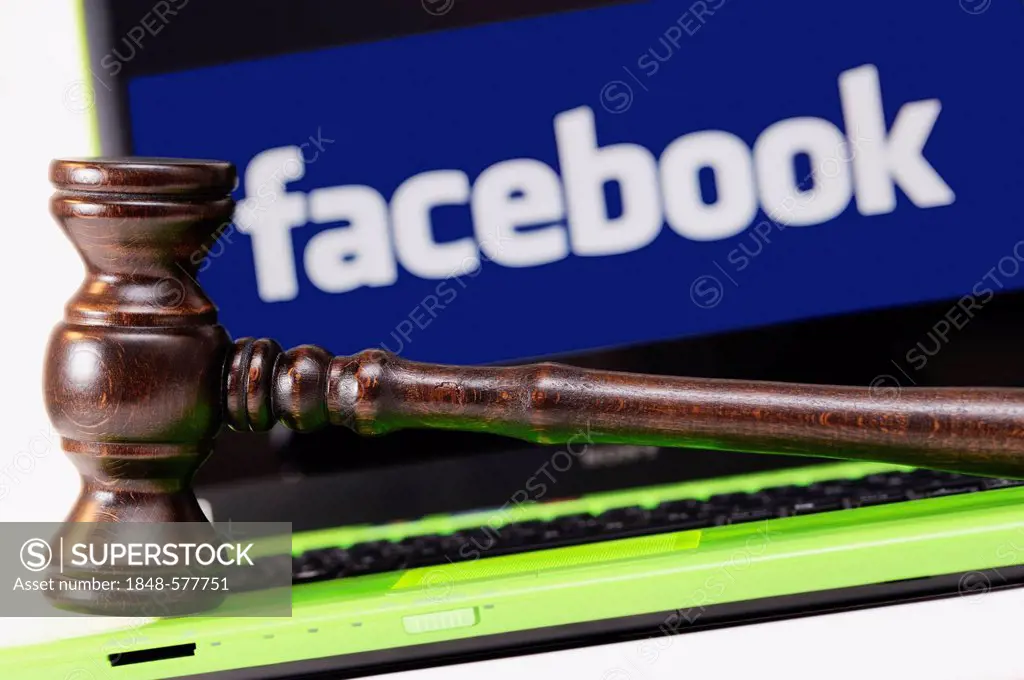 A judge's gavel in front of a laptop computer with a Facebook logo on the monitor