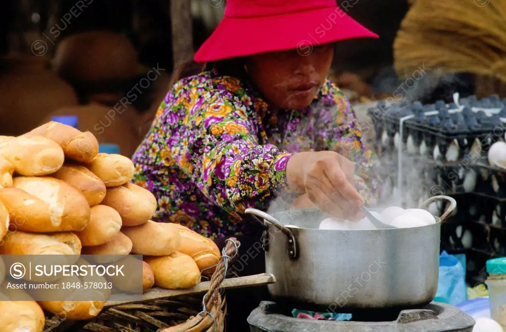 Woman boiling eggs for breakfast at one of the markets along Tonle Sap River, Kampong Chhnang, Cambodia, Southeast Asia