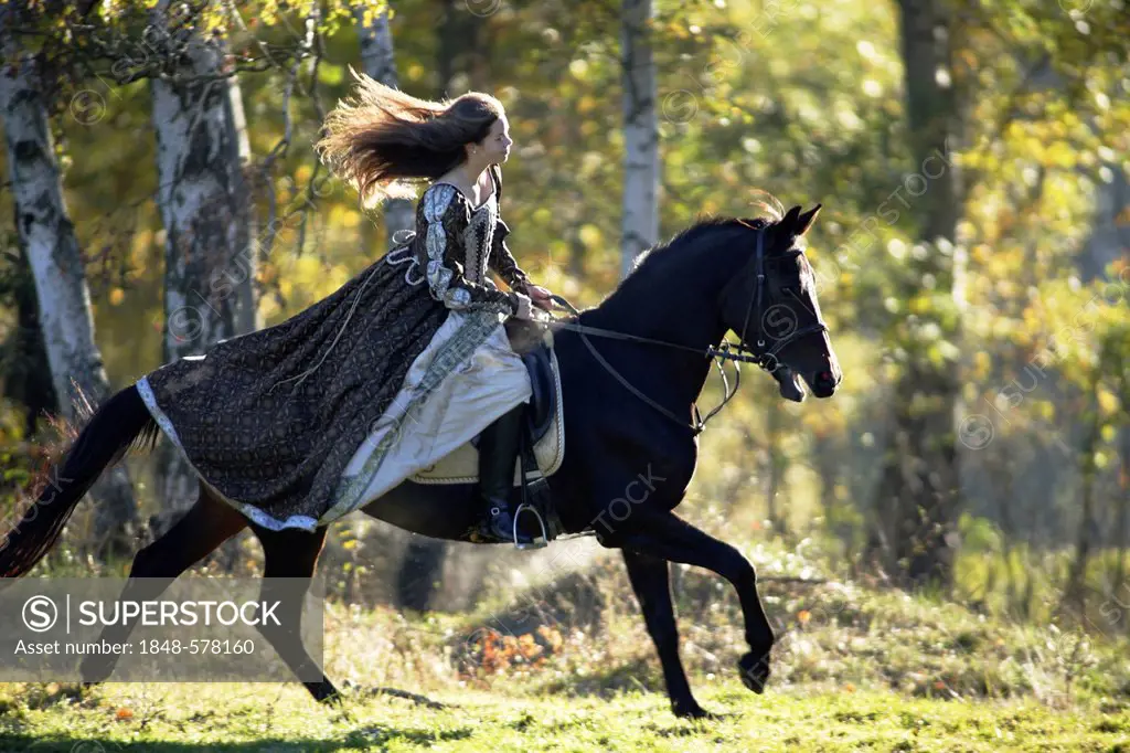 Girl, 17 years, in historic dress, 16th Century, riding horse in autumn