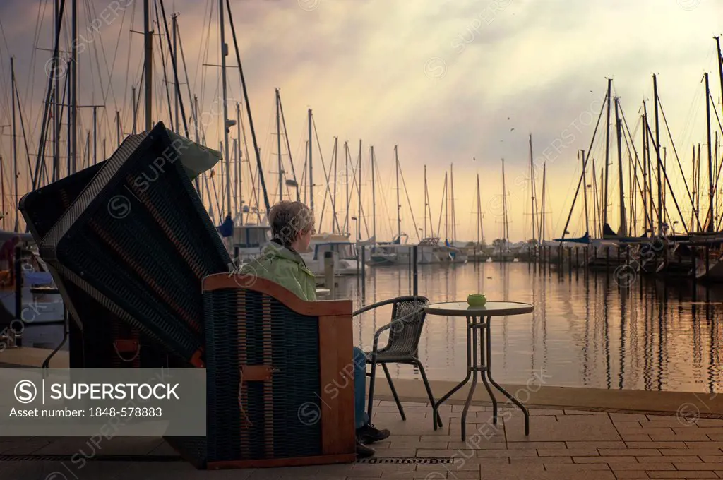 Woman sitting by the pier in Marina Heiligenhafen, Heiligenhafen, Schleswig-Holstein, Germany, Europe