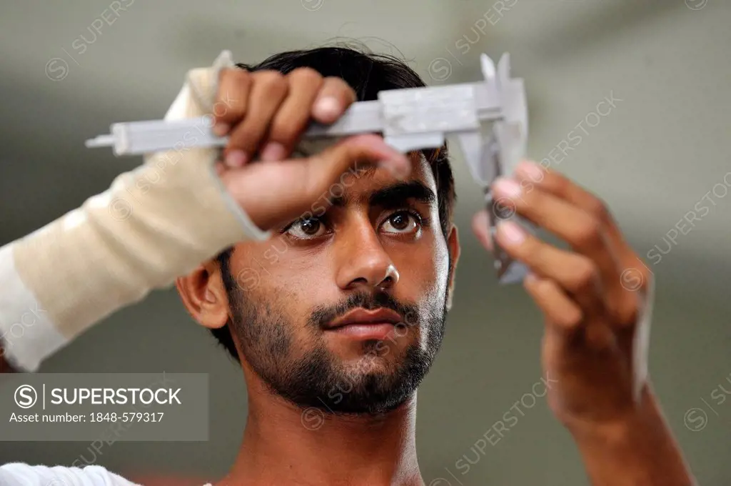 Vocational training as a metalworker, vocational student checking his work with a steel ingot for accuracy, Youhanabad, Lahore, Punjab, Pakistan, Asia