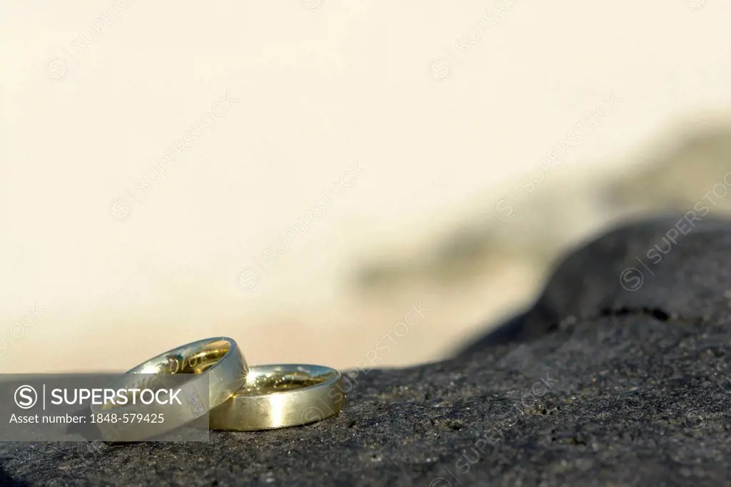 Wedding rings on a black stone on the beach of Pointe aux Piments, Mauritius, Africa