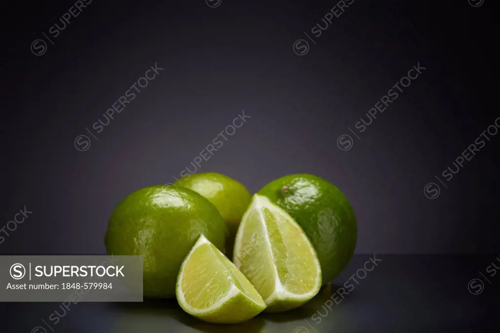 Limes (Citrus latifolia) on a dark glass surface