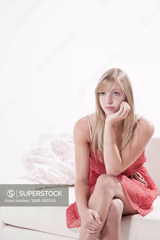 Sad young woman sitting on a sofa