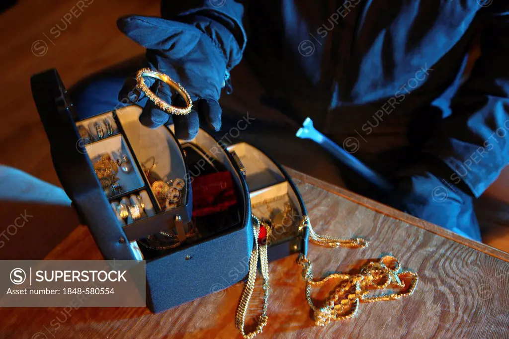 Burglar looting jewelry box, symbolic image for domestic burglary