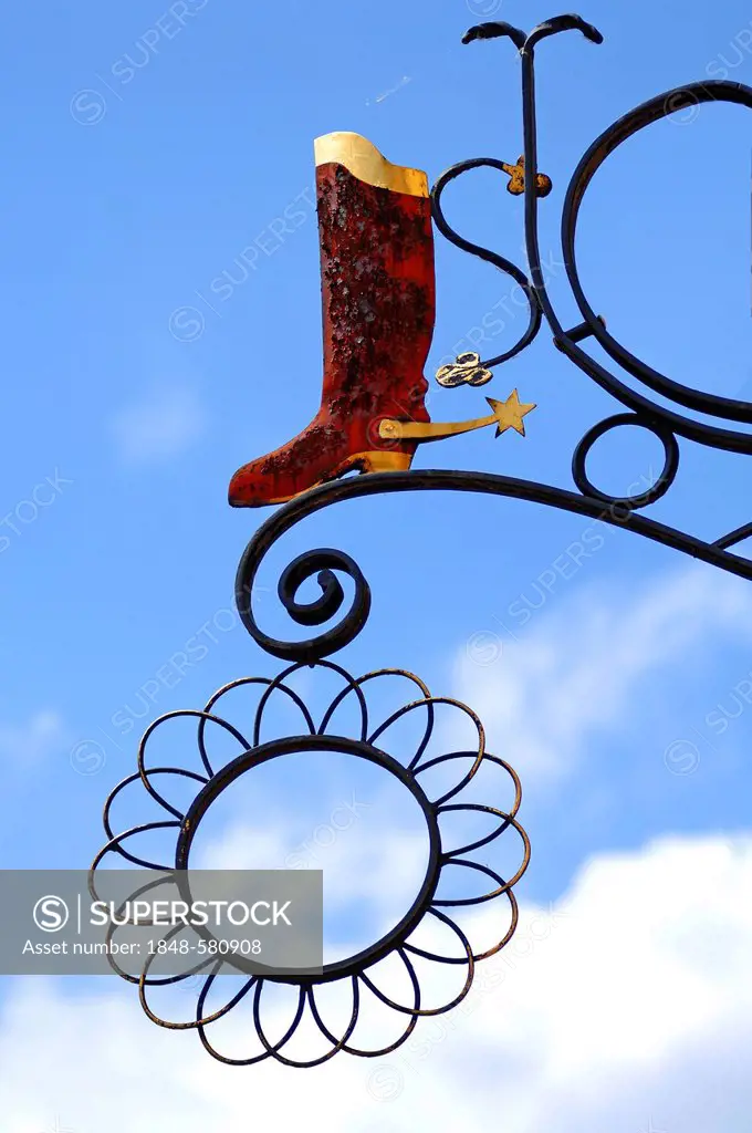 Riding boots with spurs, hanging sign of a shoe shop against a blue sky, Hauptstrasse, Gengenbach, Baden-Wuerttemberg, Germany, Europe