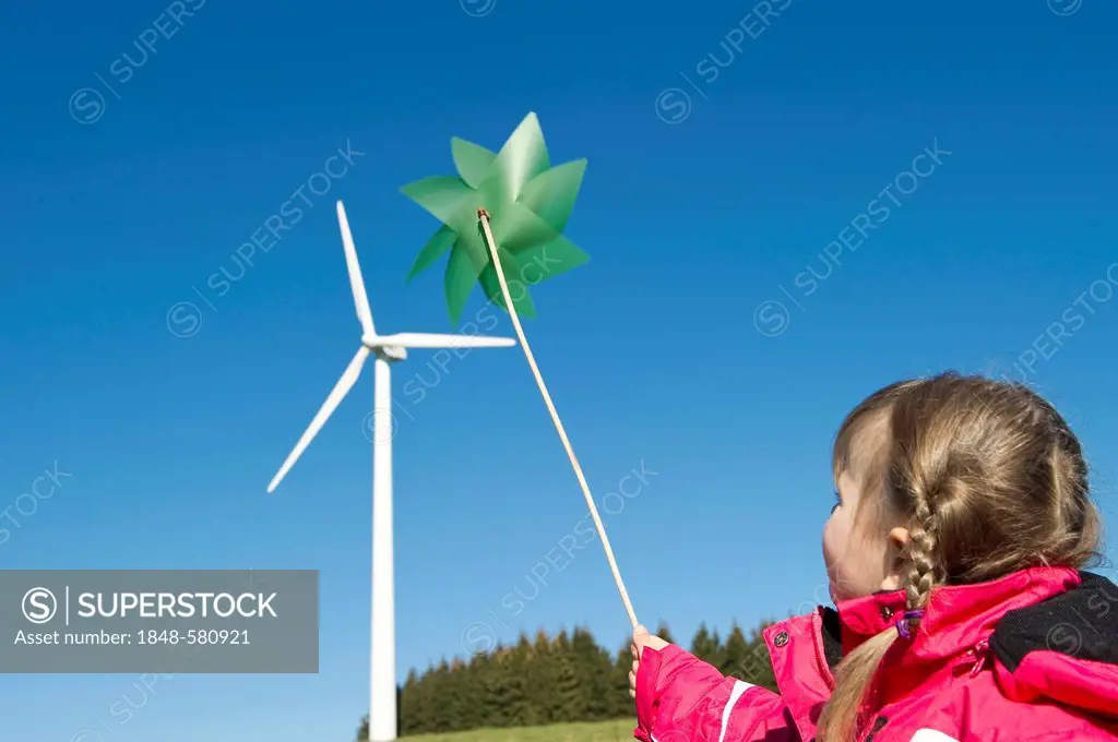 Girl holding a green pinwheel in front of a wind turbine, near Freiburg in Breisgau, Black Forest, Baden-Wuerttemberg, Germany, Europe