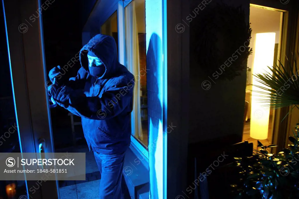 Burglar breaks open the patio door with a crowbar, symbolic image for domestic burglary