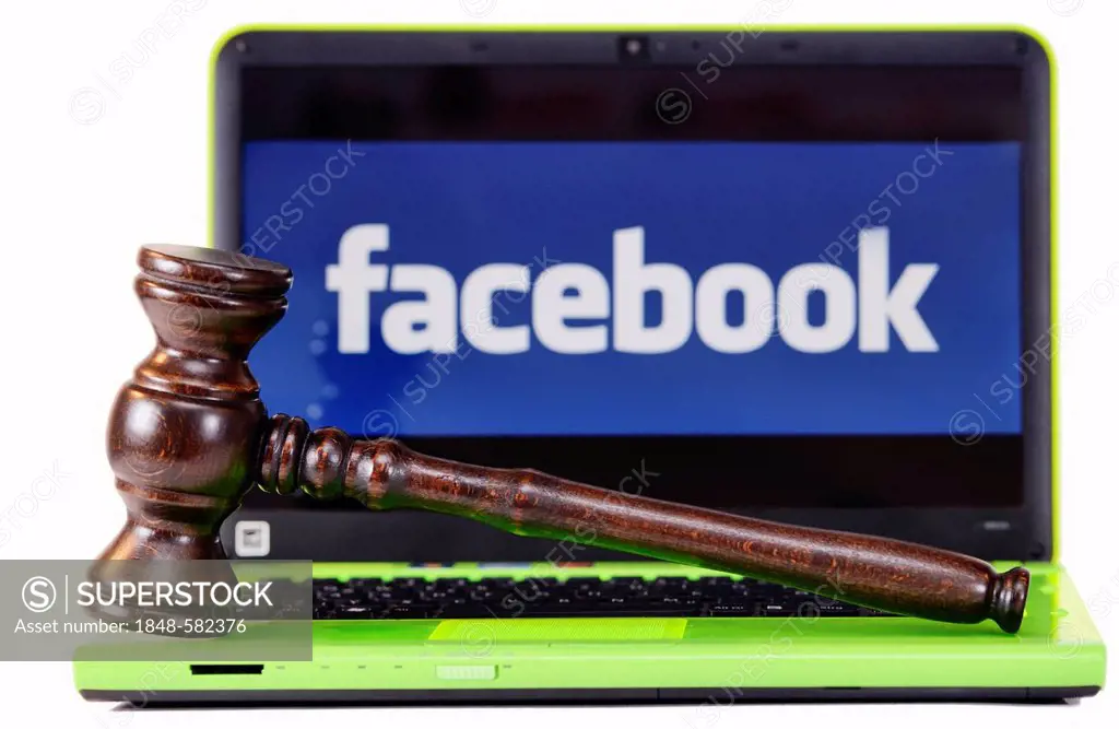 A judge's gavel in front of a laptop computer with a Facebook logo on the monitor