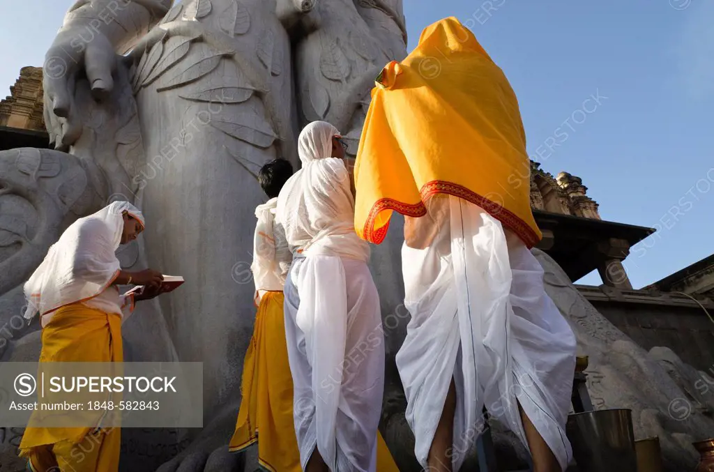 Jain pilgrims are reciting religious texts at the feet of the gigantic statue of Gomateshwara in Sravanabelagola, Karnataka, India, Asia