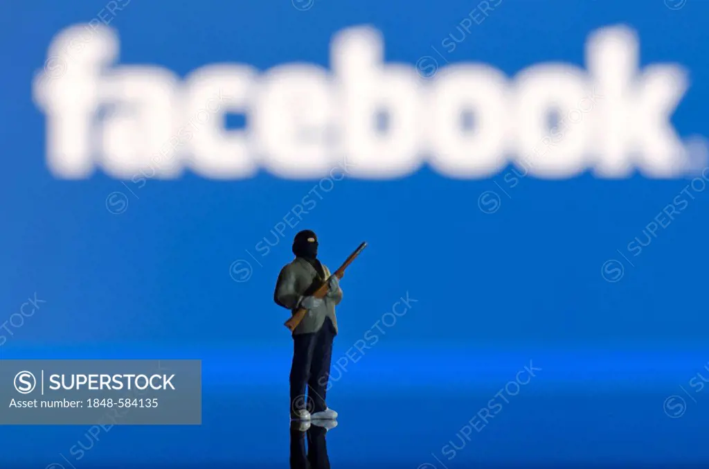 Islamist carrying a weapon, miniature figure standing in front of a blurred Facebook logo, symbolic image