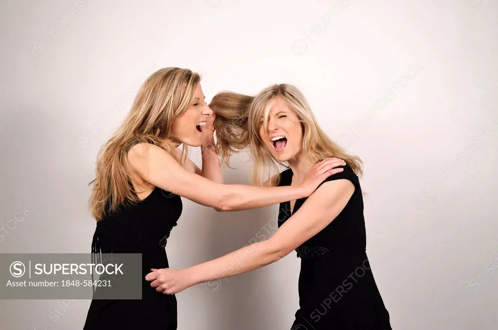 Twin sisters fighting, one sister pulling the hair of the other sister