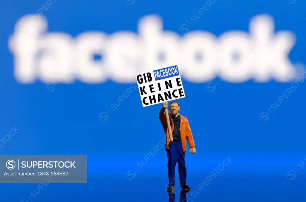 Protester holding a board, lettering Gib Facebook keine Chance, German for No chance for Facebook, miniature figure standing in front of a blurred Fac...