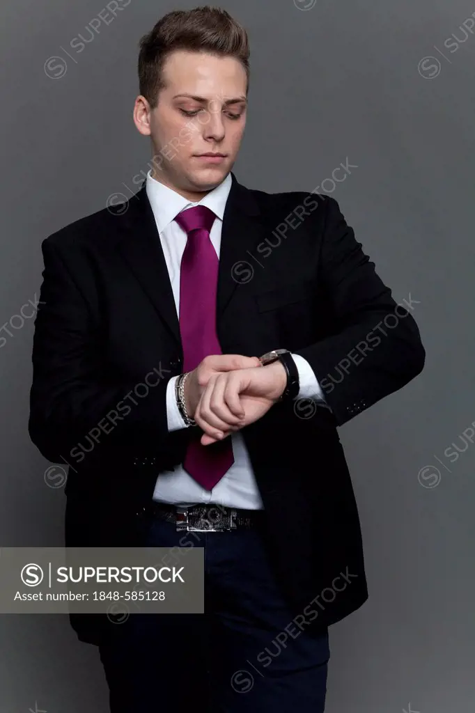 Young man in business suit and tie looking at his watch