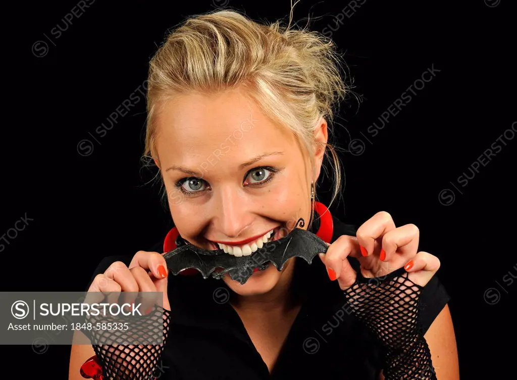 Young woman, vamp, biting into rubber bat, Halloween