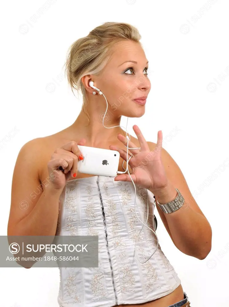 Young woman holding a white Apple iPhone, listening to music with earphones
